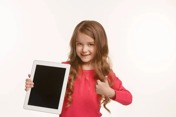 Маленькая смешная девочка с планшетом на зеленом фоне — стоковое фото