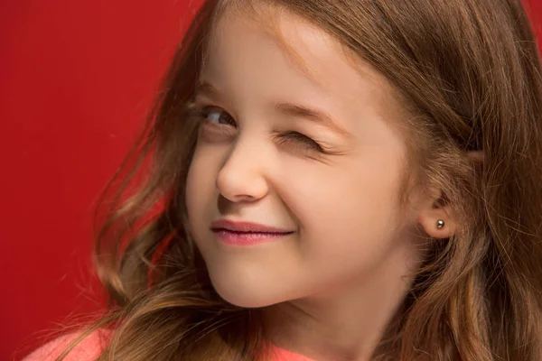 La chica adolescente feliz de pie y sonriendo contra el fondo rojo . — Foto de Stock