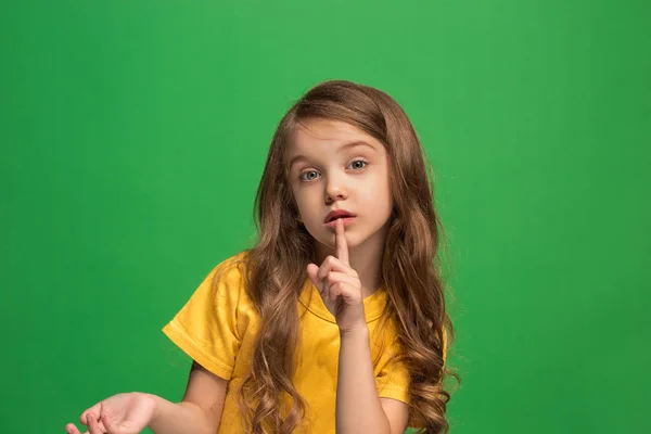 Το νεαρό κορίτσι ψιθυρίζοντας ένα μυστικό πίσω από το χέρι της σε πράσινο φόντο — Φωτογραφία Αρχείου
