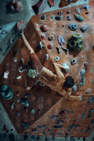 Wspinacz młody człowiek wspinaczkowe sztuczne boulder pomieszczeniu — Zdjęcie stockowe