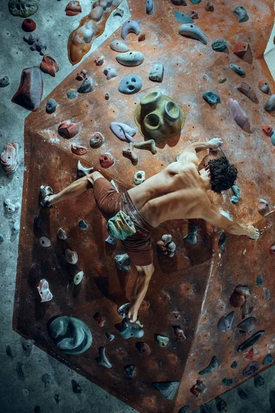 Freikletterer junger Mann klettert künstlichen Boulder drinnen — Stockfoto