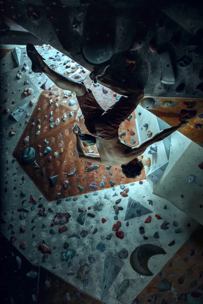 Jovem alpinista livre escalando pedregulho artificial dentro de casa — Fotografia de Stock