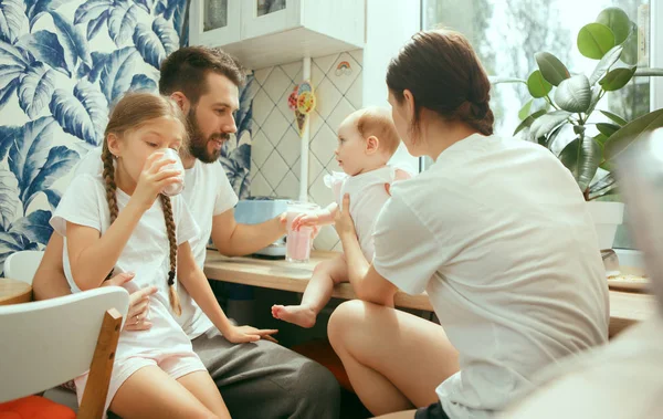 La feliz familia caucásica sonriente en la cocina preparando el desayuno —  Fotos de Stock