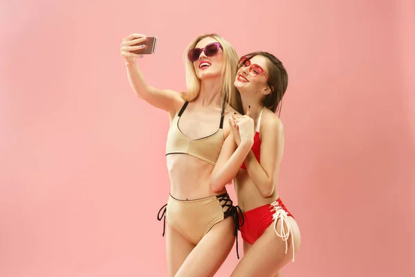 Милые девушки в купальниках позируют в студии. Летний портрет белых подростков на розовом фоне . — стоковое фото