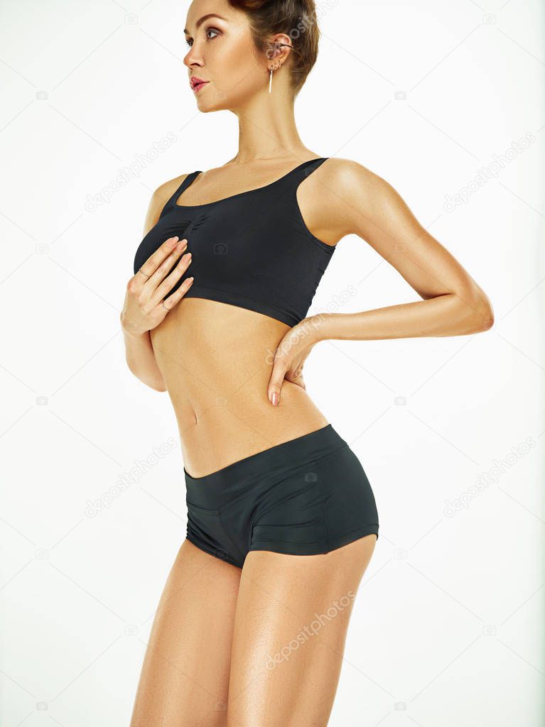 Muscular young woman athlete posing at studio