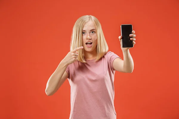 Портрет уверенной девушки с пустым экраном мобильный телефон изолирован на красном фоне — стоковое фото
