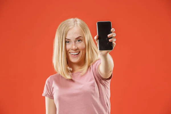 Portrét jistý neformální dívka ukazuje prázdná obrazovka mobilní telefon izolované červené pozadí — Stock fotografie