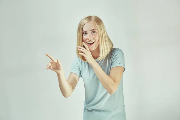 De jonge vrouw die een geheim achter haar hand fluisteren over grijze achtergrond — Stockfoto