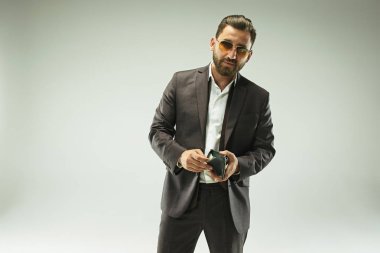 Deri çanta tutan elbiseli barded adam