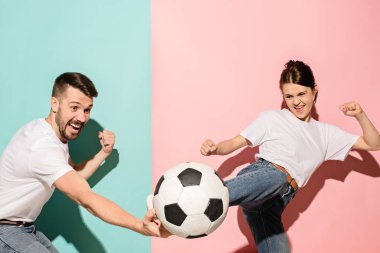 The young football fans plaing with ball on blue and pink trendy colors. clipart