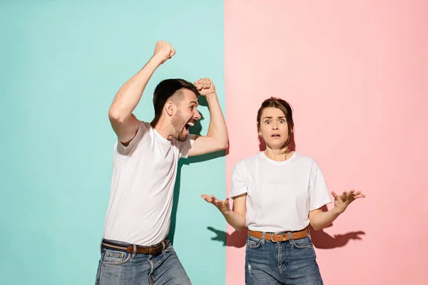 Portre portre genç çift, Erkek, kadın. Mutlu heyecanlı olmak bir gülümseyen, diğer ciddi, endişeli, pembe ve mavi arka plan üzerinde mutsuz. Duygu tezat — Stok fotoğraf