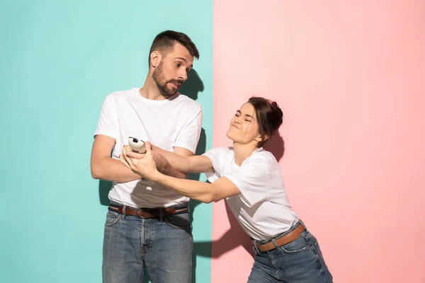 Jeune couple regarder la télévision et se battre pour obtenir la télécommande — Photo