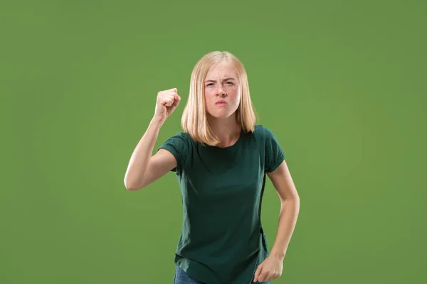 Портрет злой женщины, смотрящей в камеру на зеленом фоне — стоковое фото