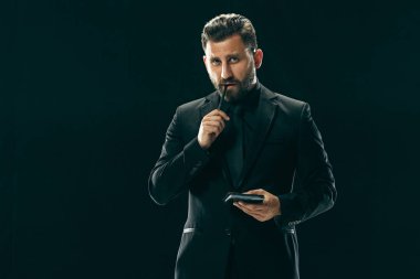 Erkek güzellik kavramı. Siyah arka plan üzerinde poz trendy elbise giymiş şık saç kesimi ile şık genç bir adam portresi.