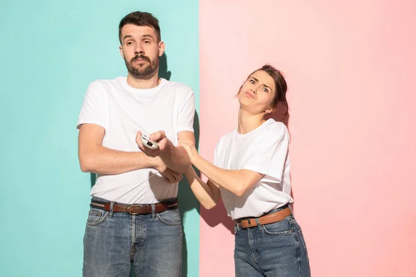 Pareja joven viendo la televisión y luchando para obtener el control remoto — Foto de Stock