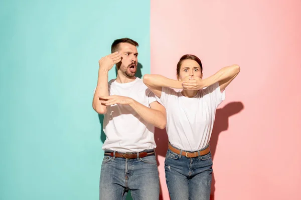 Närbild porträtt av unga par, man, kvinna. TV fläkt koncept på rosa och blå bakgrund. Emotion kontraster — Stockfoto