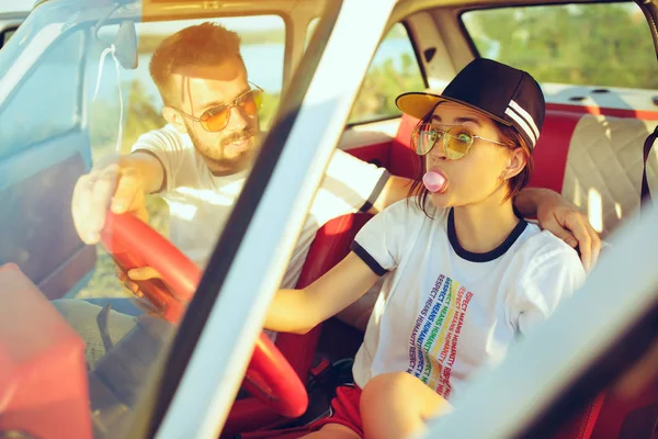 Riendo pareja romántica sentado en el coche mientras que fuera en un viaje por carretera en el día de verano —  Fotos de Stock