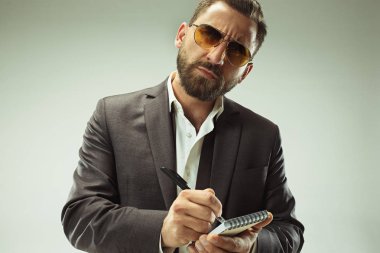 Erkek güzellik kavramı. Gri arka plan üzerinde poz trendy elbise giymiş şık saç kesimi ile şık genç bir adam portresi.