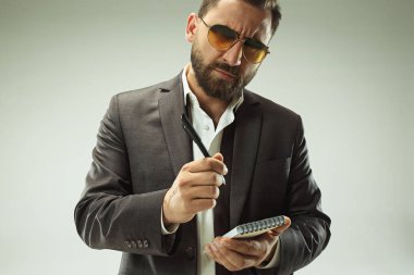 Erkek güzellik kavramı. Gri arka plan üzerinde poz trendy elbise giymiş şık saç kesimi ile şık genç bir adam portresi.