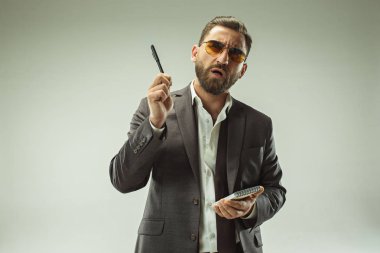 Erkek güzellik kavramı. Gri arka plan üzerinde poz trendy elbise giymiş şık saç kesimi ile şık genç bir adam portresi.