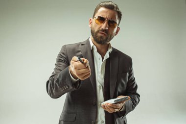 Erkek güzellik kavramı. Gri arka plan üzerinde poz trendy elbise giymiş şık saç kesimi ile şık genç bir adam portresi.