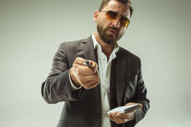 Erkek güzellik kavramı. Gri arka plan üzerinde poz trendy elbise giymiş şık saç kesimi ile şık genç bir adam portresi.
