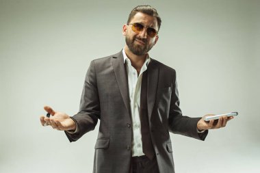 Erkek güzellik kavramı. Gri arka plan üzerinde poz trendy elbise giymiş şık saç kesimi ile şık genç bir adam portresi.