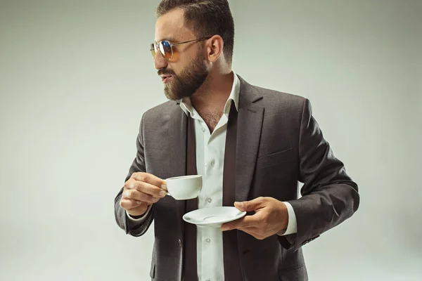 Il concetto di bellezza maschile. Ritratto di un giovane alla moda con taglio di capelli elegante che indossa abito alla moda posa su sfondo grigio . — Foto Stock