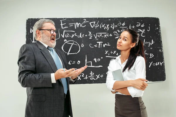 Mannelijke professor en jonge vrouw tegen schoolbord in de klas — Stockfoto