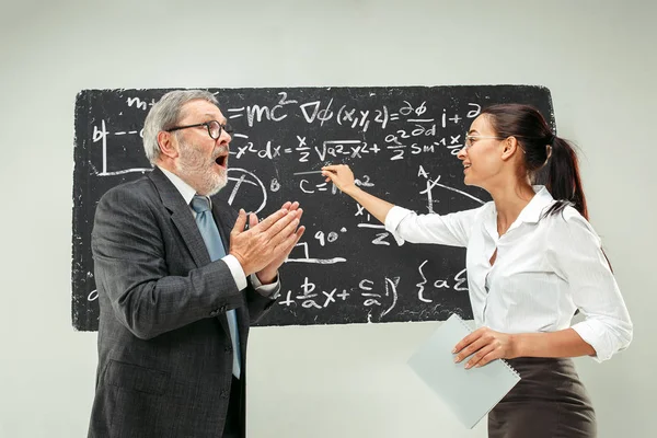 Profesor muž a mladá žena proti tabule v učebně — Stock fotografie