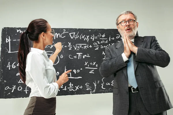 Profesor muž a mladá žena proti tabule v učebně — Stock fotografie