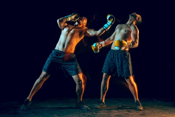 Boxer maschile boxe in uno studio buio — Foto Stock