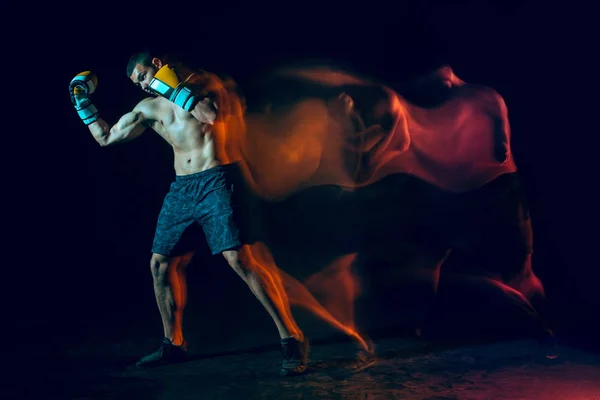 Male boxer boxing in a dark studio — Stock Photo, Image