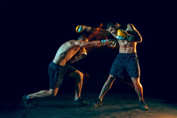 Male boxer boxing in a dark studio — Stock Photo, Image