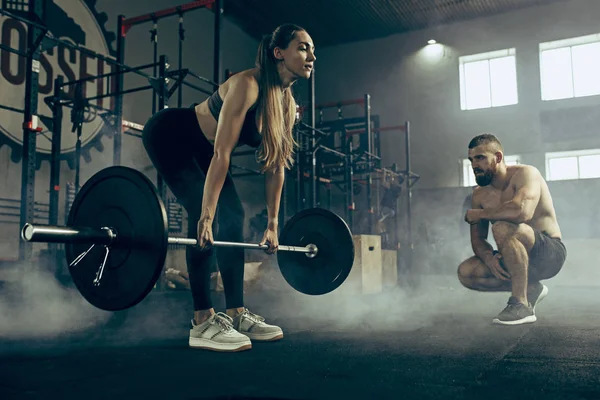 Fit jonge vrouw opheffing halters trainen in een sportschool — Stockfoto