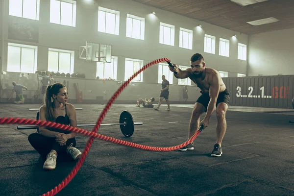 Los hombres con cuerdas de batalla se ejercitan en el gimnasio de fitness . — Foto de Stock