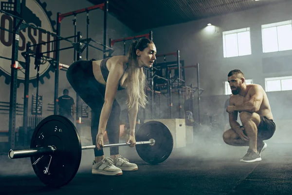 Fit jonge vrouw opheffing halters trainen in een sportschool — Stockfoto