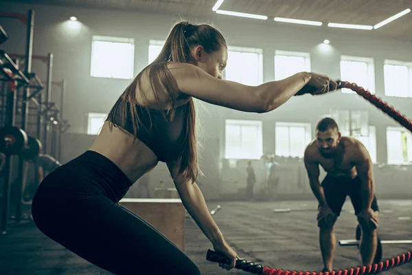 Vrouw met strijd touwen oefening in de fitness-sportschool. — Stockfoto