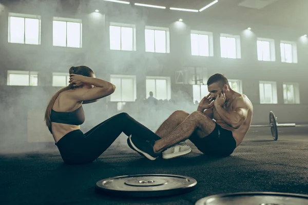 Hombre y mujer durante los ejercicios en el gimnasio. CrossFit . — Foto de Stock