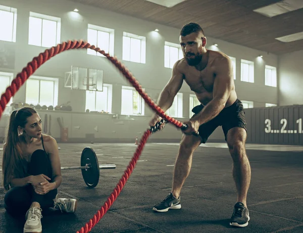 Men with battle rope battle ropes exercise in the fitness gym.