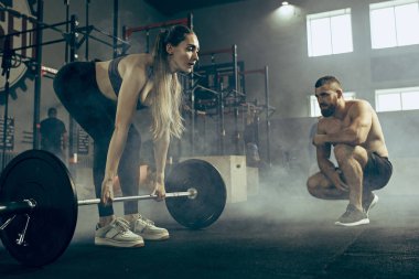 Uygun genç kadın bir spor salonunda egzersiz barbell kaldırma