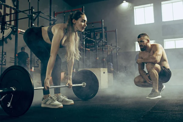 Fit jonge vrouw opheffing halters trainen in een sportschool — Stockfoto