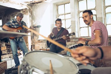 Rock müzik grubu tekrarı. Elektro gitar çalar ve davulcu arkasında davul seti.