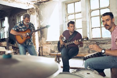 Rock müzik grubu tekrarı. Elektro gitar çalar ve davulcu arkasında davul seti.