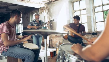Rock müzik grubu tekrarı. Elektro gitar çalar ve davulcu arkasında davul seti.