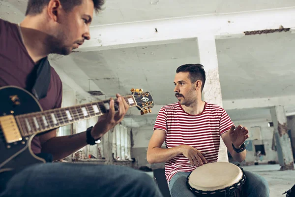 Repetition of rock music band. Electric guitar player and drummer behind the drum set.