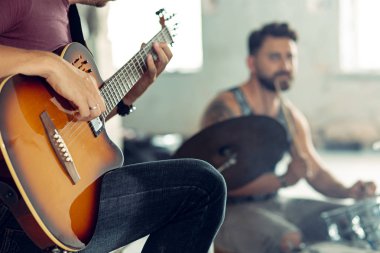 Rock müzik grubu tekrarı. Elektro gitar çalar ve davulcu arkasında davul seti.