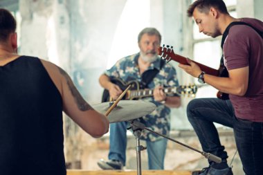 Rock müzik grubu tekrarı. Bas gitarist, elektro gitar çalar ve çatı, davulcu. Rock müzik ve reçel oturum kavramı. tutku müzik ve gençlik kültürü kavramları