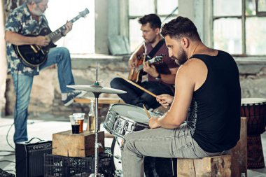 Rock müzik grubu tekrarı. Elektro gitar çalar ve davulcu arkasında davul seti.