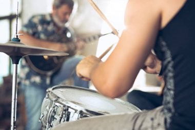 Rock müzik grubu tekrarı. Elektro gitar çalar ve davulcu arkasında davul seti.